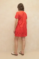 Vestido corto negro con escote redondo, mangas cortas con detalle de calado y falda escalonada con detalle de calado en el ruedo.