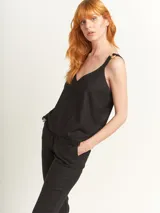 Top negro con escote en V y breteles con argollas de madera. Ruedo con flecos.