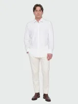 Camisa blanca de manga larga con corte slim fit, confeccionada en jersey elástico de alto rendimiento con sutil estampado. Cuenta con cuello camisero clásico y cierre frontal de botones.
