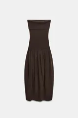 Vestido midi de corte bandeau con escote palabra de honor y detalle de vuelta en el pecho. Presenta una cintura entallada con pliegues y una falda con volumen en tejido combinado a tono.