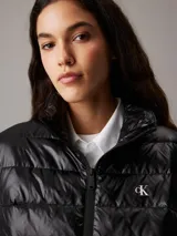 Chaleco puffer negro Calvin Klein Essentials, con cuello alto, cierre de cremallera, bolsillos laterales y logo estampado en el pecho.