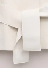 Chaqueta de mezcla de lana, poliéster y elastano color marfil, con solapas cruzadas, cuello alto y cinturón ajustable del mismo tejido. Cuenta con mangas largas y forro interior de viscosa.