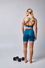 Top deportivo color beige con contorno inferior y tiras cruzadas en la espalda color borgoña. Cuenta con almohadillas removibles.