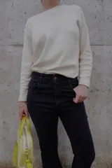 Sweater de punto color crema, con cuello redondo y mangas largas.