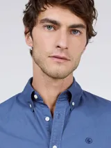 Camisa de hombre de corte regular fit, color gris oscuro, confeccionada en algodón con acabado vintage de tintado en prenda. Cuenta con cuello button-down, cierre frontal de botones, manga larga y logo bordado en el pecho.