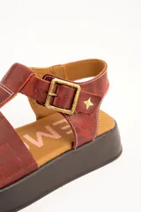 Sandalia cangrejera de plataforma color marrón rojizo, confeccionada en 100% cuero con efecto desgastado. Posee tiras anchas en el empeine, tira con hebilla metálica en el tobillo y detalle de estrella dorada grabada.