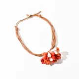 Collar con cordón marrón y colgante de cuentas de plástico rojas, naranjas y blancas.