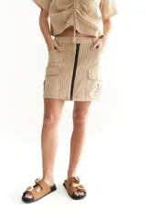 Falda mini color beige, de lino, con cierre frontal con cremallera y bolsillos laterales tipo cargo.