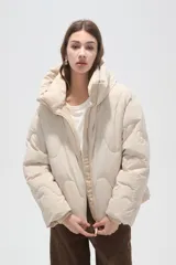 Campera puffer de cuello alto con capucha integrada, cierre frontal y diseño acolchado con costuras onduladas. Presenta mangas largas y bolsillos laterales.