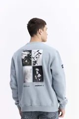 Buzo de algodón color celeste, con cuello redondo, puños y bolsillos laterales. Presenta estampados con texto en el pecho y un parche en la manga.