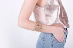 Brazalete rígido dorado con forma de sol.