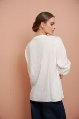 Camisa blanca de manga larga con escote redondo, puntillas y tablas al frente.