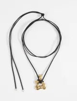 Collar con cordón de gamuza negro y dije dorado con forma de flor irregular.