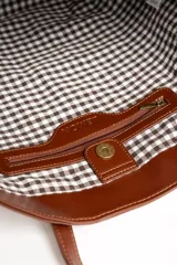 Bolso tipo tote bag color marrón, confeccionado en cuero sintético, con doble asa superior y detalle de placa metálica dorada con logo en la parte frontal.