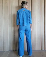 Pantalón de denim estilo palazzo, color azul claro, con cintura elástica en la parte posterior, bolsillos frontales y costuras verticales decorativas a lo largo de las piernas.