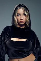 Canguro corto negro de terciopelo con capucha, mangas largas abullonadas con puños elastizados y abertura en el pecho.