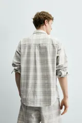 Camisa regular fit confeccionada en tejido de algodón con diseño de cuadros en tonos celestes y beige, cuello con botones, manga larga con puño abotonado y bolsillo de parche en el pecho.