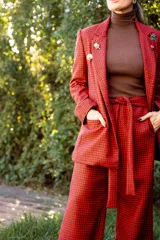 Pantalón de pierna recta con estampado de cuadros en tonos rojo y negro. Presenta cintura alta con lazo ajustable, elástico en la parte posterior de la pretina y cierre lateral.