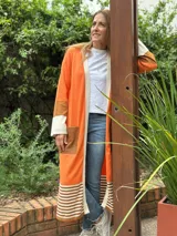 Saco largo color naranja de tejido de punto en algodón, con solapas y bolsillos de cuero marrón.