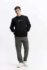 Buzo negro de algodón con cuello redondo, puños y cintura elásticos. Presenta un pequeño estampado frontal con texto en azul claro.