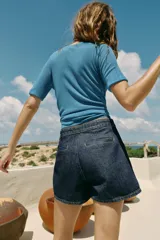 Falda pantalón cruzada de denim en color celeste, con diseño cruzado al frente, cierre frontal oculto y hebilla decorativa redonda en la cintura.