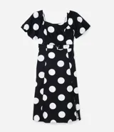Vestido midi de algodón con estampado de lunares blancos sobre fondo negro. Presenta escote en V, mangas cortas abullonadas, cintura ajustada con cinturón de hebilla y falda con tajo lateral.