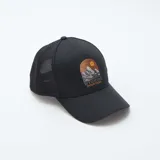 Gorra negra con visera curva y paneles traseros de malla. Presenta un bordado frontal con un paisaje de montañas y el texto "Wyoming Mountains".