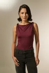 Top sin mangas color bordó, confeccionado en poliamida, con cuello recto y detalle de frunces laterales que le otorgan un ajuste al cuerpo.