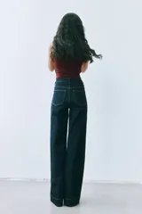 Pantalón de jean tiro alto, color azul oscuro, de corte ancho y pierna recta. Presenta costuras en hilo contrastante y grandes bolsillos parche delanteros y traseros.