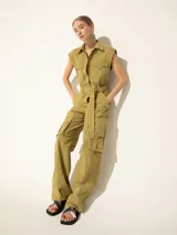Mono color verde oliva, con cuello camisero, sin mangas, bolsillos frontales y laterales tipo cargo, y cinturón de lazo.