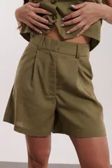 Short color verde militar, de tiro alto con pinzas y bolsillos laterales.