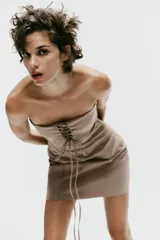 Vestido mini taupe de escote palabra de honor y hombros descubiertos, con detalle de tejido superpuesto y tiras cruzadas ajustables en el pecho. Cuenta con cierre lateral con cremallera oculta.