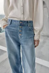 Jeans de tiro alto, color celeste claro con efecto desgastado y lavado. Modelo de corte holgado (loose baggy) con cierre frontal de botones metálicos y cinco bolsillos.