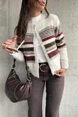 Cardigan de punto con diseño a rayas horizontales en tonos crema, marrón y bordó. Presenta cuello redondo, cierre frontal con botones y mangas largas.