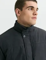 Campera de estilo Harrington en color verde oscuro, con cuello alto, cierre frontal y solapa con botones.