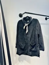 Sobrecamisa negra de pana con cuello camisero y cierre frontal con botones.