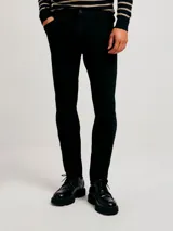 Pantalón de jean corte skinny, color azul medio, con diseño de cinco bolsillos y cierre frontal con botón y cremallera.