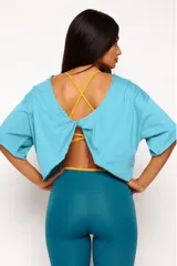 Remera corta de manga corta color celeste, con escote amplio en la espalda que se anuda en la parte inferior, dejando ver un top deportivo amarillo con tiras cruzadas.