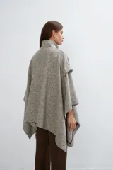 Capa de lana fina con cuello alto, cierre frontal con botones ocultos y bolsillos plaqué. Presenta aberturas laterales versátiles que permiten usarla como poncho o ruana, con terminaciones envivadas.