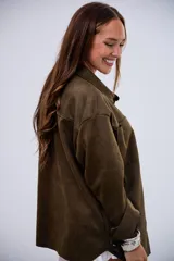 Sobrecamisa de gamuza en color verde militar, con corte oversize, cuello clásico, cierre frontal con botones metálicos y bolsillos frontales tipo parche.