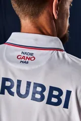 Camiseta de fútbol Umbro del Club Nacional de Football, modelo Home 2026. Diseño blanco con cuello en V, detalles en azul y rojo en el cuello y las mangas, y patrón en tejido jacquard. Incluye el logo de Umbro, el escudo del club y el sponsor antel en el pecho.