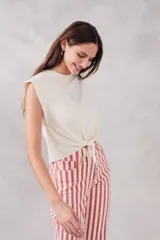 Top de algodón peinado color crudo, con cuello redondo, hombreras marcadas y detalle de nudo frontal ajustable.