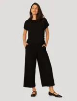 Conjunto de dos piezas en tejido acanalado color negro. La remera es de manga corta raglán, cuello redondo y cuenta con frunces laterales con cordón ajustable. El pantalón es de corte recto y holgado, con cintura elástica y bolsillos laterales.