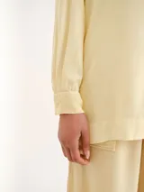 Camisa amarilla de manga larga, con cuello camisero clásico y cierre frontal de botones.