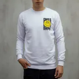 Buzo blanco de algodón con cuello redondo y mangas largas. Estampado en el pecho con una cara sonriente amarilla y texto negro "SMILE" y "DUXON CO.".