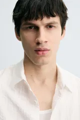 Camisa de corte relajado confeccionada en tejido fluido con textura acanalada. Presenta cuello solapa, manga corta y cierre frontal con botones.