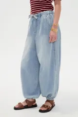 Pantalón jean de corte globo con cintura elástica y cordón ajustable, tiro medio y botamangas fruncidas con elástico.