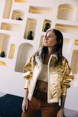 Campera oversize de cuero tostado con solapas y forro interno de corderito sintético azul marino, mangas anchas y detalles de costuras trenzadas.