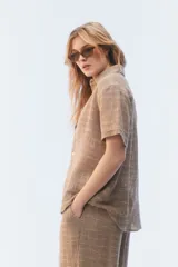 Camisa amplia y relajada de algodón liviano color blanco, de trama abierta y textura, con cuello camisero, mangas cortas y cierre de botones al frente.