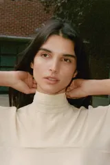 Top tipo capa de color beige, con cuello subido y cierre posterior con botones ocultos. Presenta un diseño fluido con bajo asimétrico y mangas acampanadas.